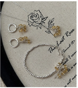 Detail view of S925 silver jewelry set with yellow quartz on vintage rose background