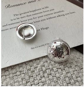 Macro view of S925 silver stud earrings with hammered texture and rope edge detail