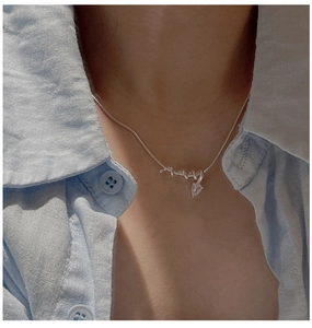 Detail of S925 silver snake chain with clear pear-shaped crystal pendant on model