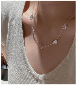 Detailed close-up of S925 silver necklace featuring hollow heart pendants on a model
