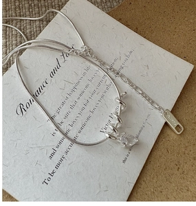 Detail of S925 silver snake chain with teardrop zircon pendant on vintage paper