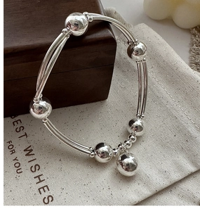 Dettaglio di un bracciale in argento S925 con sfere lucide su panno di lino