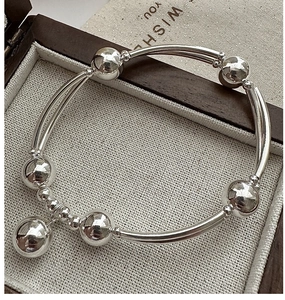 Dettaglio del bracciale in argento S925 con perline e tubi curvi su fodera in lino