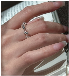 Close-up of minimalist S925 sterling silver beaded ring worn on a finger over a book