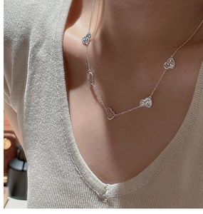 Detail of S925 sterling silver multi-heart pendant necklace on a beige knit sweater