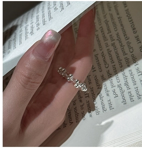 Macro shot of S925 silver beaded ring with clear crystals worn over an open book