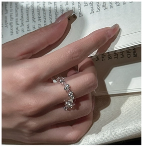 Macro view of beaded S925 sterling silver ring with white crystal on hand with book background