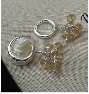 Macro shot of S925 silver asymmetric earrings with citrine beads and spiral shell pendant