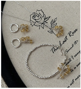 Flat lay of S925 silver jewelry set with yellow citrine stones and vintage poem background