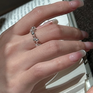 Minimalist S925 sterling silver beaded ring worn on hand over an open book background
