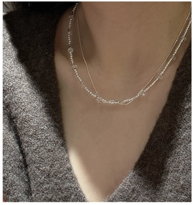 Macro detail of layered S925 sterling silver beaded necklace with clear crystal pendant