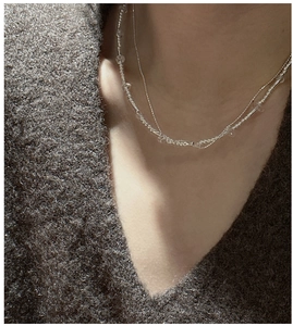 Close-up of double-layered S925 silver chain with beads and clear crystal on a sweater