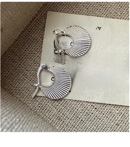 Macro detail of retro silver fan-shaped earrings with fine pleated radial textures