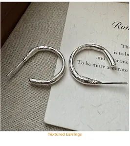 Macro shot of silver S925 earrings with unique spiral texture on rustic linen fabric