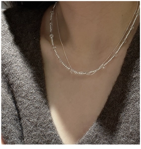 Detail of layered S925 silver necklace with beads and white crystals on a model