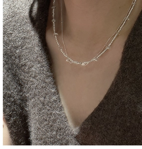 Detail of double-layered S925 silver necklace with white crystal beads on a model