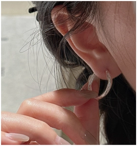 Detail of silver hoop earring with vintage hammered texture worn on earlobe