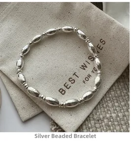 Detail of S925 sterling silver beaded bracelet with polished oval beads on a linen bag
