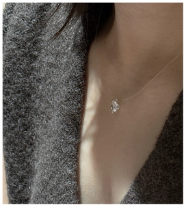 Detail of hidden fishing line necklace with sparkling zircon floating on the collarbone