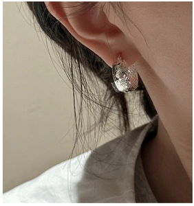 Macro view of silver hoop earrings with diamond-cut texture and shimmering finish