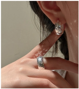 Close-up of hammered S925 sterling silver earrings and matching ring on model