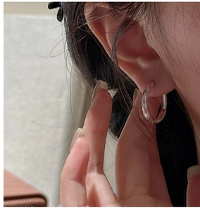 Close-up of minimalist S925 sterling silver hoop earrings with a polished glossy finish