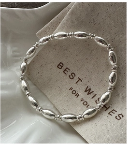 Close-up of S925 sterling silver beaded bracelet on a ceramic tray with a linen pouch