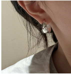 Close-up of a textured S925 sterling silver hoop earring worn on a model's ear