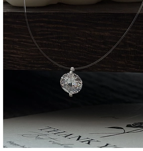 Macro view of a single round-cut zircon pendant on a transparent fishing line necklace