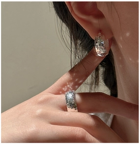 Detailed view of shimmering textured silver jewelry set with hammered finish in soft light