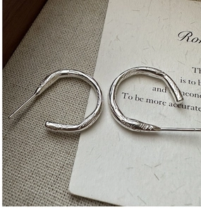 Macro detail of S925 sterling silver hoop earrings with unique organic lava texture