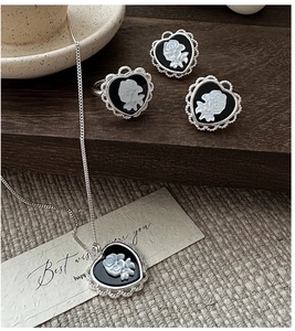 Macro detail of vintage black cameo heart jewelry set with white rose floral carvings
