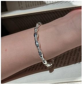 Macro detail of polished S925 sterling silver olive bead bracelet worn on wrist