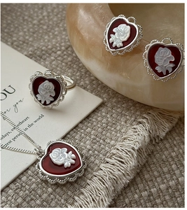 Detailed macro view of S925 silver vintage heart jewelry set with red rose cameo accents