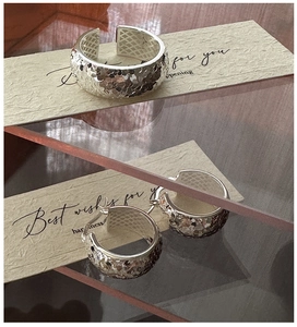 Macro detail of silver ring and earrings with textured hammered ice pattern surfaces