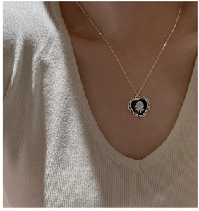 Gros plan du collier médaillon cœur en argent S925 avec camée rose blanche sur noir