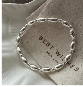 Macro shot of silver beaded bracelet with oval olive beads and threaded ring accents