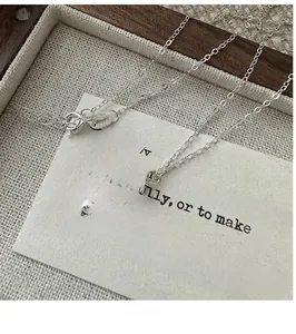 Gros plan sur chaîne en argent S925 avec pendentif fleur en perle baroque sur lin