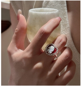 Close-up of S925 silver vintage heart ring with red cameo rose on a hand holding a cup