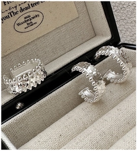Macro detail of silver C-shape hoop earrings with vintage beaded texture in a jewelry box