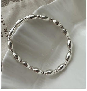 Detailed view of S925 sterling silver beads with vertical textures on white ceramic