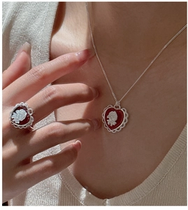 Detail of vintage S925 silver necklace and ring set with red heart rose cameo