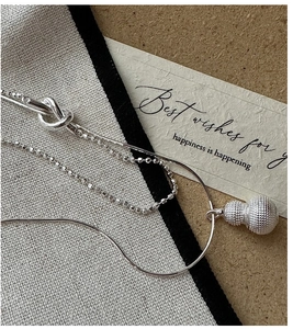 Macro shot of silver layered necklace with textured gourd pendant on elegant fabric