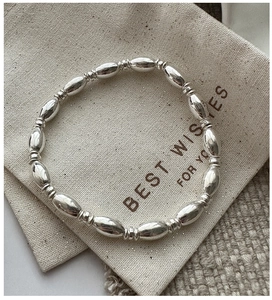 Detailed shot of S925 silver beaded bracelet on a gift canvas pouch background
