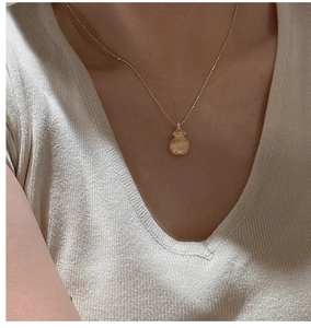 Macro shot of a vintage S925 silver lucky bag pendant on a gold necklace on a model