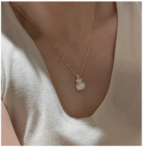 Close-up of S925 sterling silver lucky bag pendant necklace on a knitted sweater