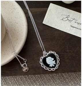 Détail du collier coeur en argent S925 avec camée rose sur fond de bois sombre