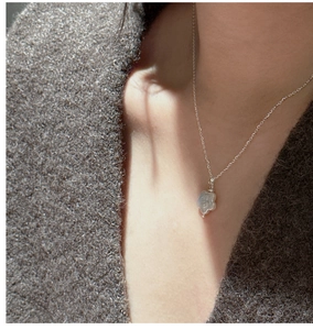 Détail du collier en argent S925 avec pendentif fleur de perle sur pull gris