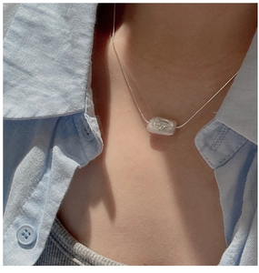 Detailed view of Baroque pearl pendant on fine silver chain worn on person's neck