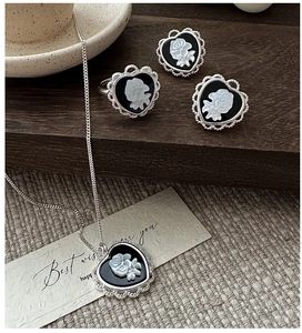 Detail view of S925 silver cameo jewelry set with white rose motif on a wooden background
